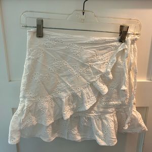 White eyelet mini skirt with a wrap around ruffle. By Princess Polly.